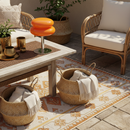 Outdoor patio with wicker furniture, table, and decorative items on a patterned rug.