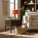 Living room with a beige sofa, wicker side table, and orange lamp.