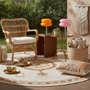Outdoor patio with wicker chair, colorful stools, and decorative elements.