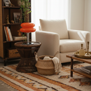 Living room with beige armchair, wicker side table, and patterned rug.