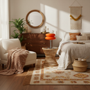 Cozy bedroom with wooden dresser, white chair, and bed with pillows.