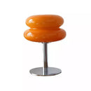 Orange cylindrical stool with a metallic base on a white background