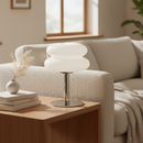 Modern table lamp on a wooden side table with a cozy living room background