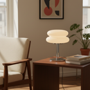 Modern table lamp on a wooden side table in a living room setting with a chair and plant.