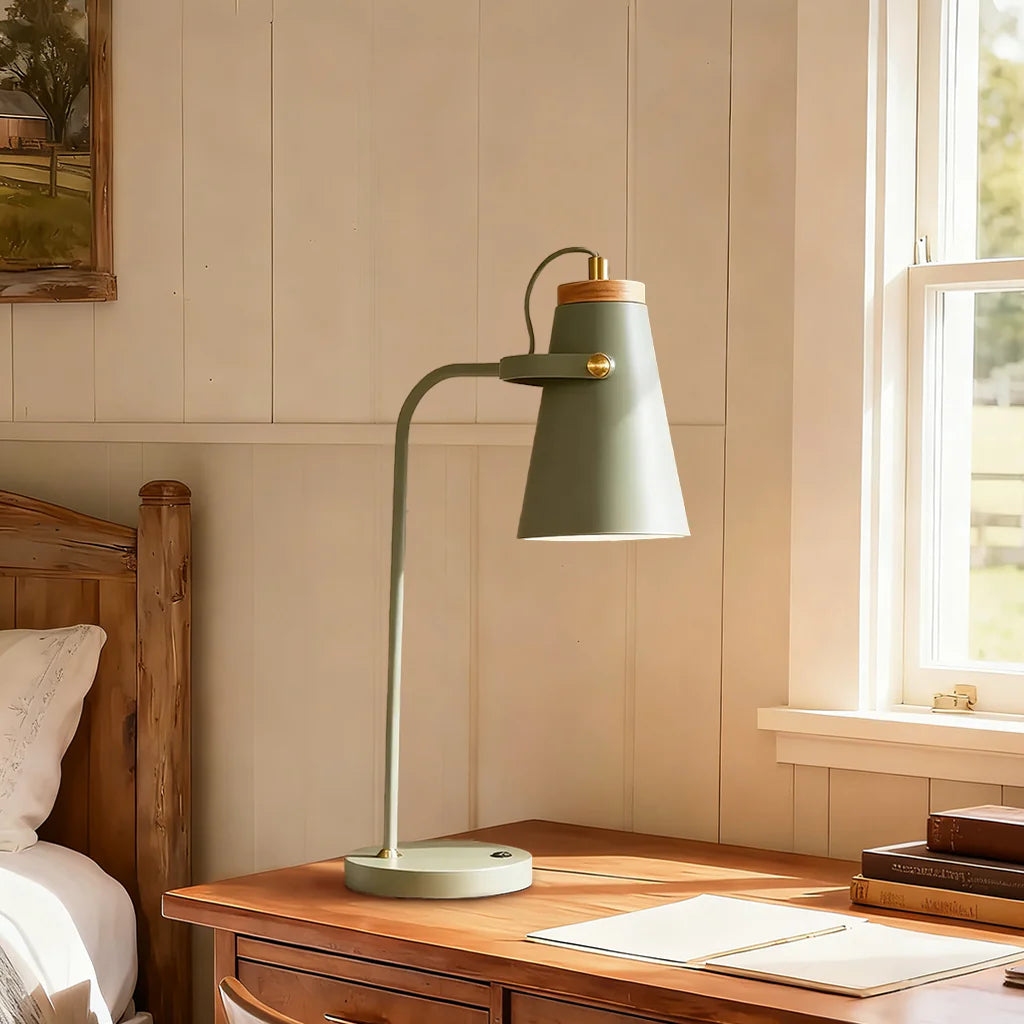 Green desk lamp on a wooden desk with a window in the background