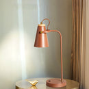 Pink desk lamp on a round table with a soft background