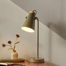 Table lamp with a vase of flowers on a wooden surface against a neutral wall.