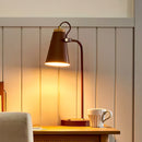Wooden desk with lamp and mug against a wooden panel wall