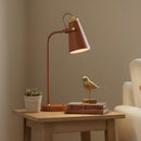 Brown table lamp on a wooden side table with decorative items against a beige wall.