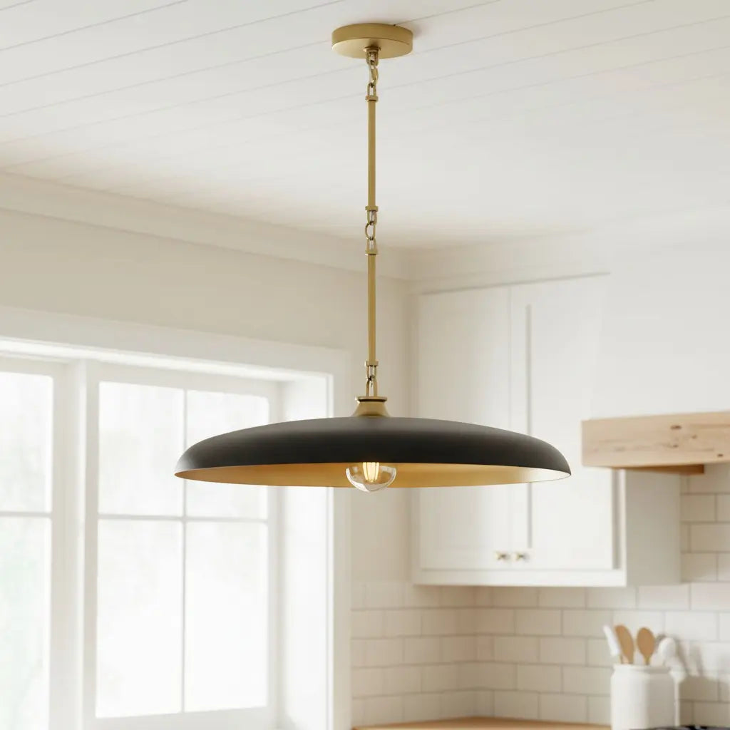 Black pendant light hanging in a kitchen with white cabinets and a window.