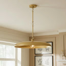 Gold pendant light hanging in a room with neutral walls and framed pictures.