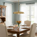 Dining room with a wooden table set for dinner, gold pendant light, and flowers in a vase.
