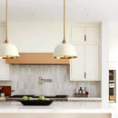 Modern kitchen with white countertops, wooden cabinets, and pendant lights.