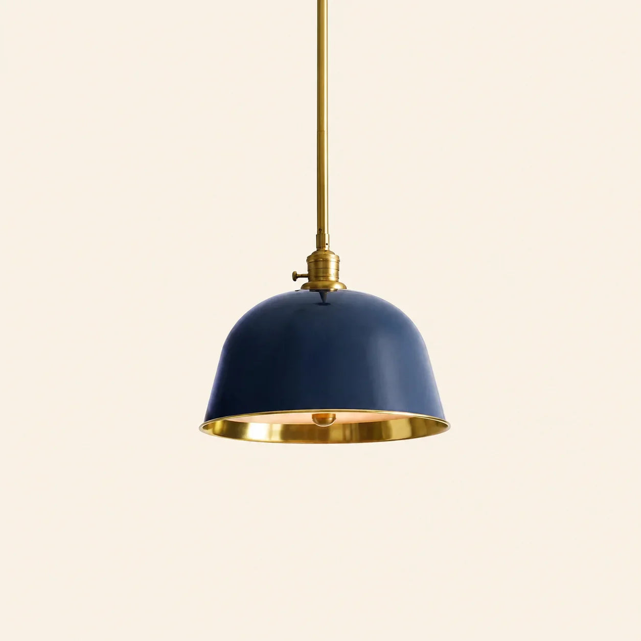 Pendant light with navy blue shade and gold trim on a beige background