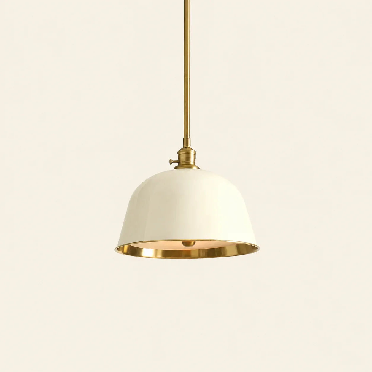 Pendant light with white shade and gold metal accents on a beige background