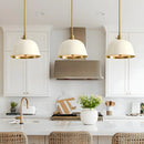 Modern kitchen with white cabinets, gold fixtures, and pendant lights.