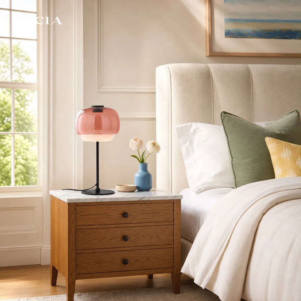 Bedroom with wooden nightstand, pink lamp, and floral arrangement.