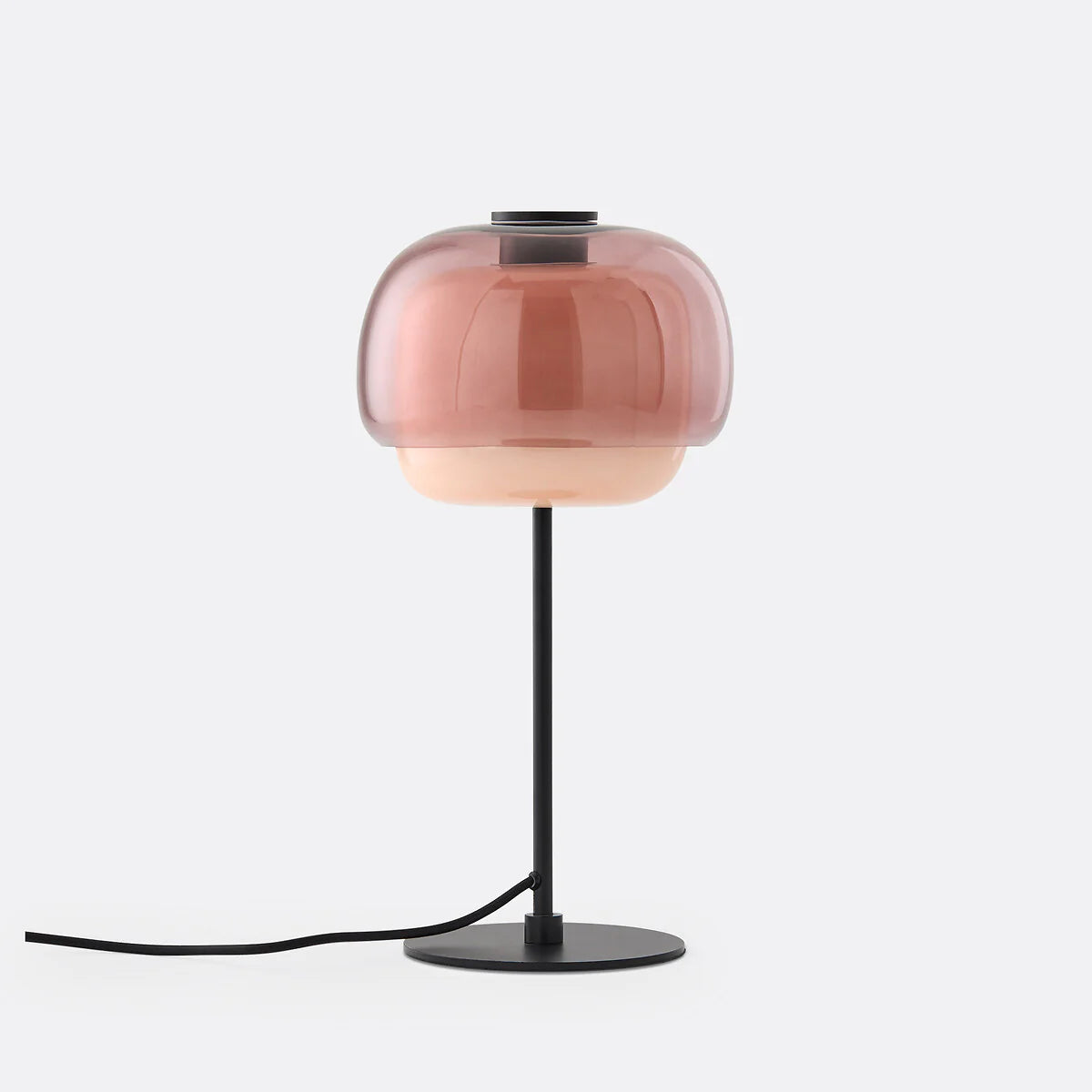 Table lamp with a pink glass shade and black base on a white background