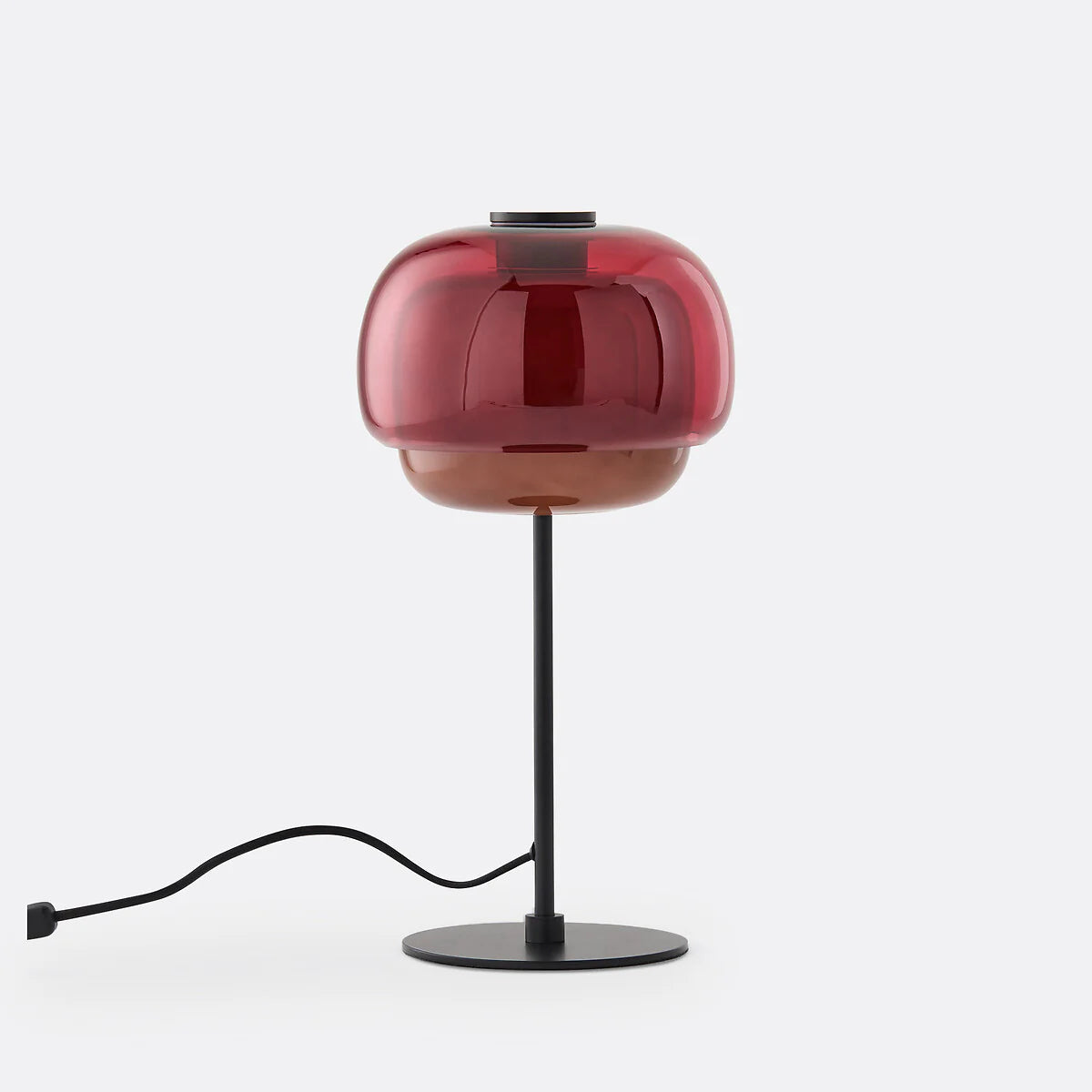 Modern table lamp with red glass shade and black base on a white background
