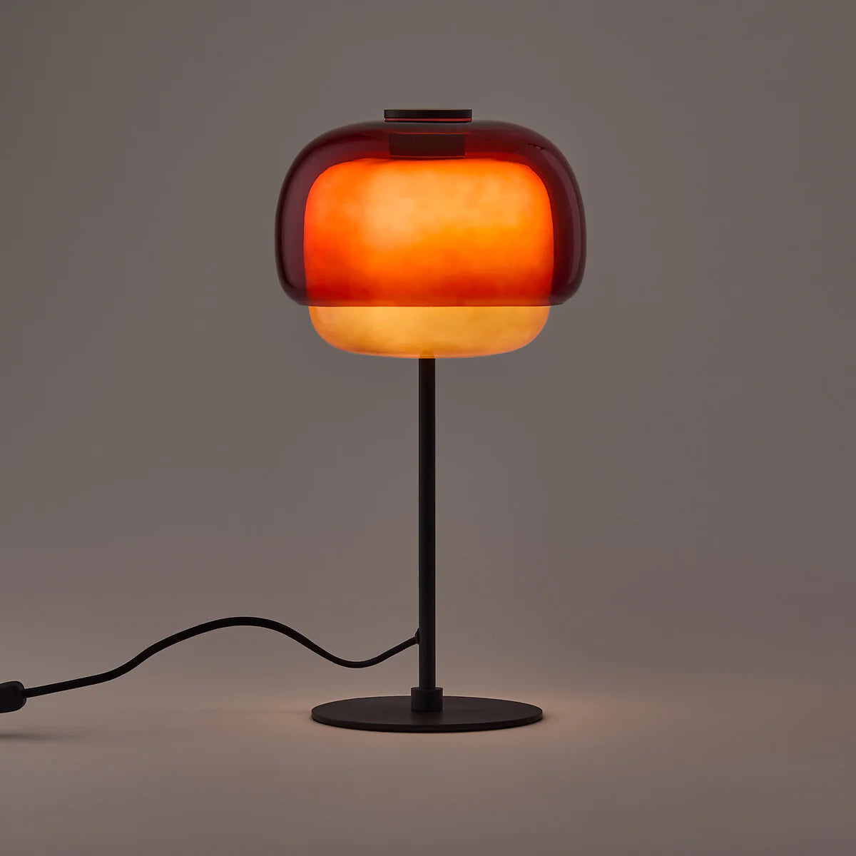 Table lamp with a glowing orange shade on a dark background