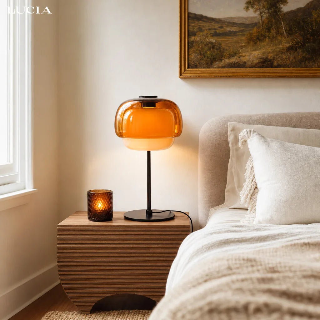 Bedroom with an orange table lamp on a wooden nightstand, soft lighting.