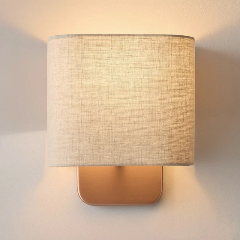 Wall-mounted lamp with a textured beige shade on a neutral wall.