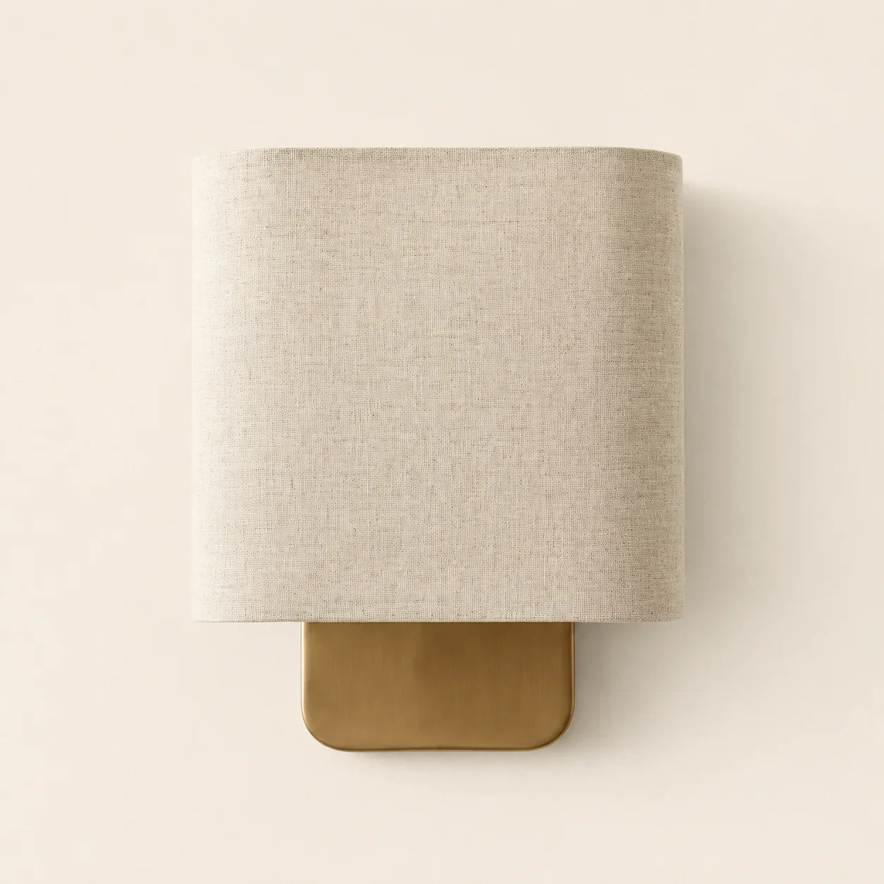 Wall-mounted lamp with beige fabric shade and gold base on a white background
