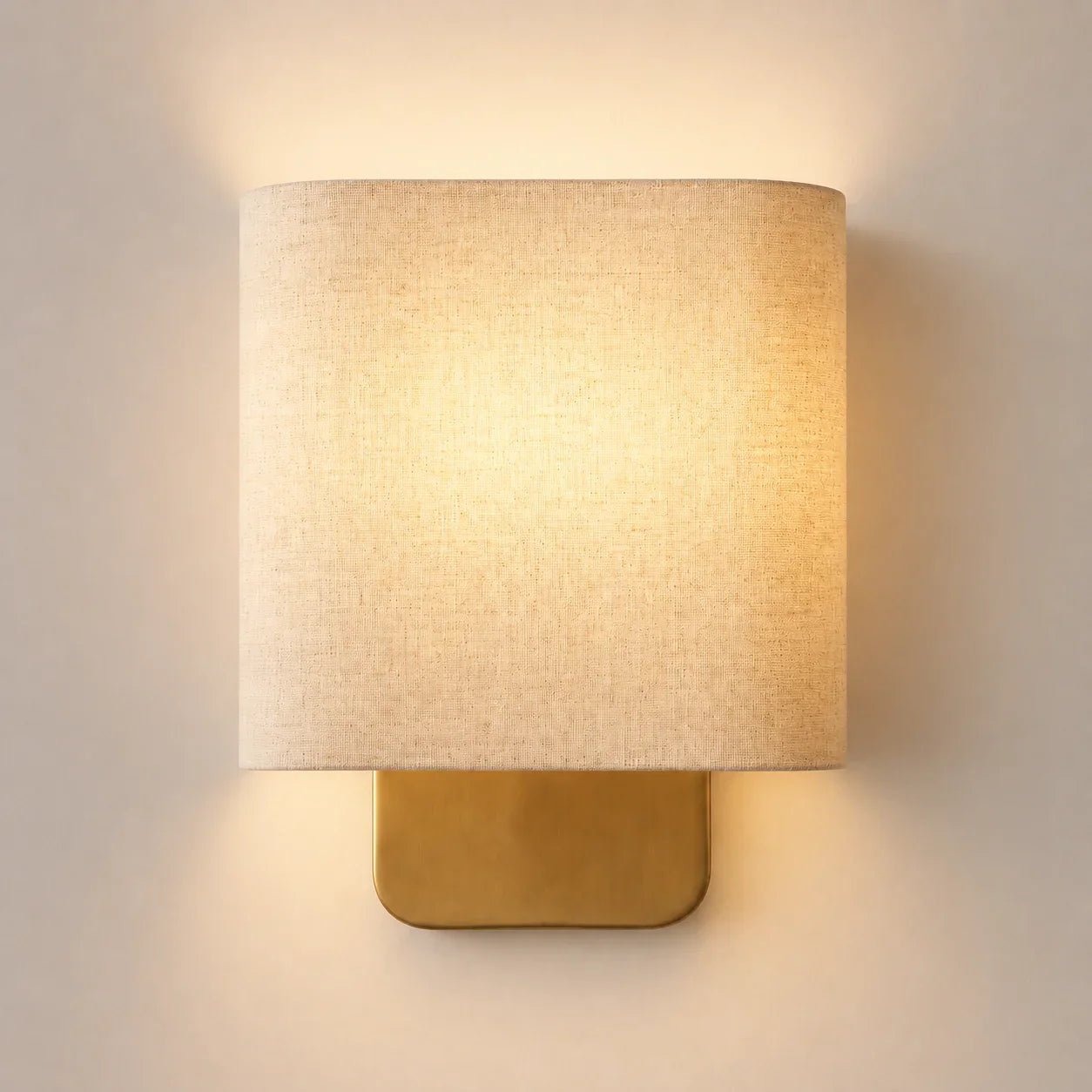 Wall-mounted lamp with a beige shade and gold base on a light gray background