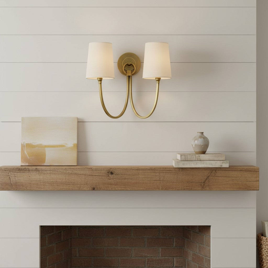 Two-light wall sconce above a fireplace with decorative items on a mantel.