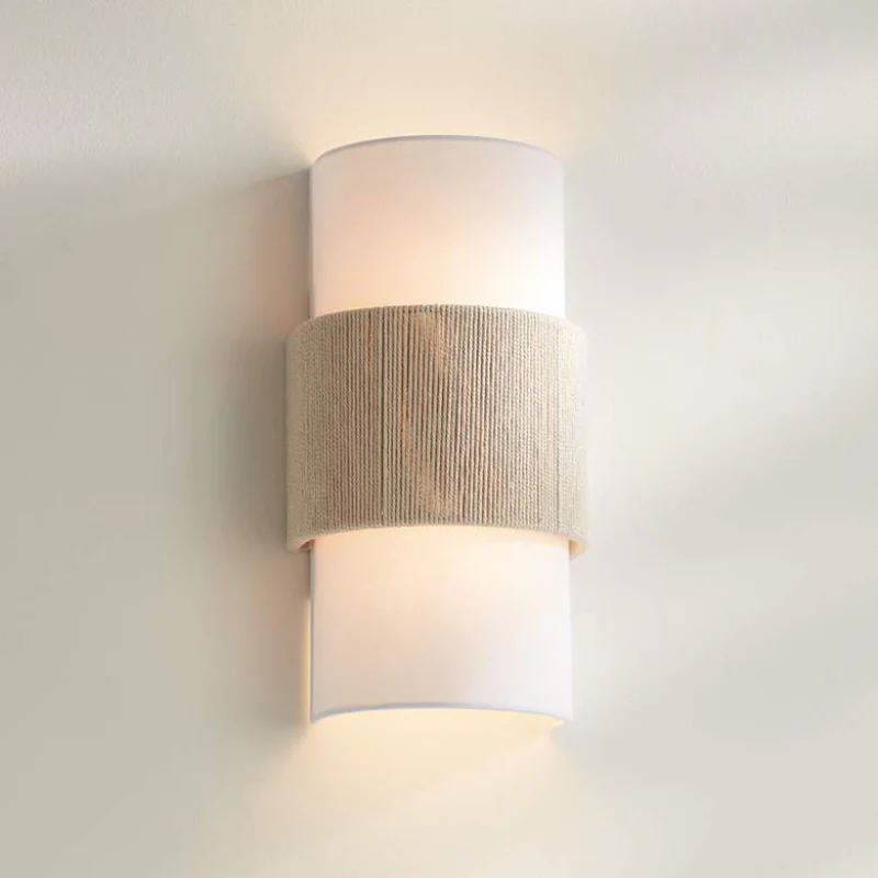 Wall-mounted light fixture with two cylindrical shades on a plain wall.