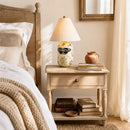 Bedroom with wooden nightstand, lamp, and decorative items.