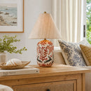 Decorative lamp on a wooden table with a couch and painting in the background