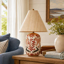 Decorative lamp with floral design on a wooden table in a living room setting.