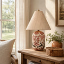 Decorative lamp with floral design on a wooden table by a window