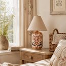 Decorative lamp on a wooden nightstand with books, a plant, and a basket in a cozy bedroom setting.