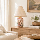 Living room with a lamp, books, and plants on a wooden side table.