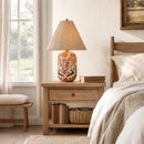 Nursery room with wooden nightstand, floral-patterned lamp, and books.
