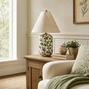 Living room with a lamp on a wooden side table, plants, and a sofa.