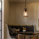 Cozy nook with a bench, table, and pendant light in a room with wooden paneling.