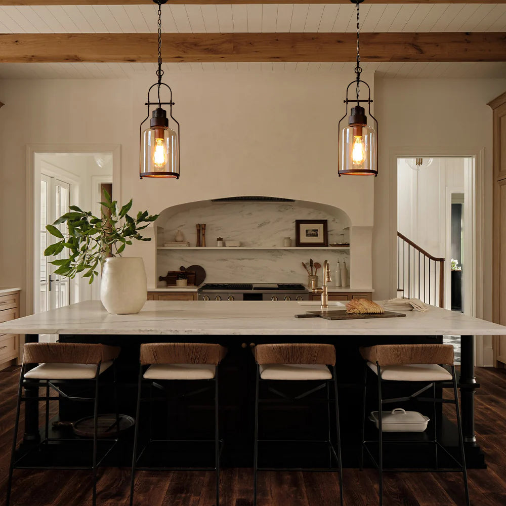 Modern kitchen with marble island, pendant lights, and wooden chairs.