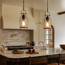 Modern kitchen with pendant lights, marble island, and wooden chairs.