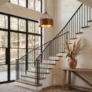 Staircase with black railings and a vase of dried plants on a wooden table.