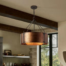 Copper pendant light hanging in a room with wooden beams and a window.