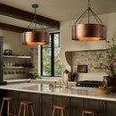 Modern kitchen with copper pendant lights, marble countertops, and wooden stools.