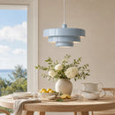 Dining room with a light blue pendant lamp, table setting, and vase with flowers.