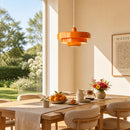 Dining room with wooden table, chairs, and an orange pendant light.