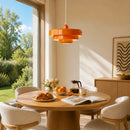 Dining area with a round table, chairs, and a bright orange pendant light.