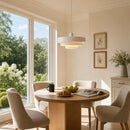 Modern dining room with a round wooden table, chairs, and large windows.