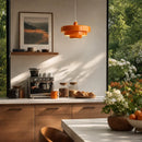 Modern kitchen with a coffee machine, orange pendant light, and outdoor view.