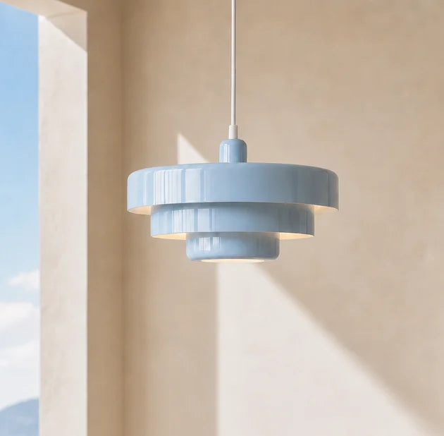 Blue pendant light hanging against a beige wall with sunlight casting shadows.